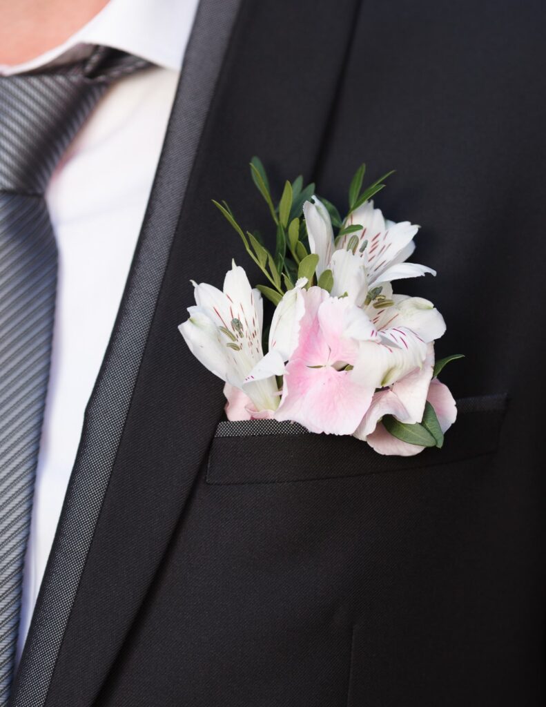 groom wearing a pocket boutonniere with pink and white flowers