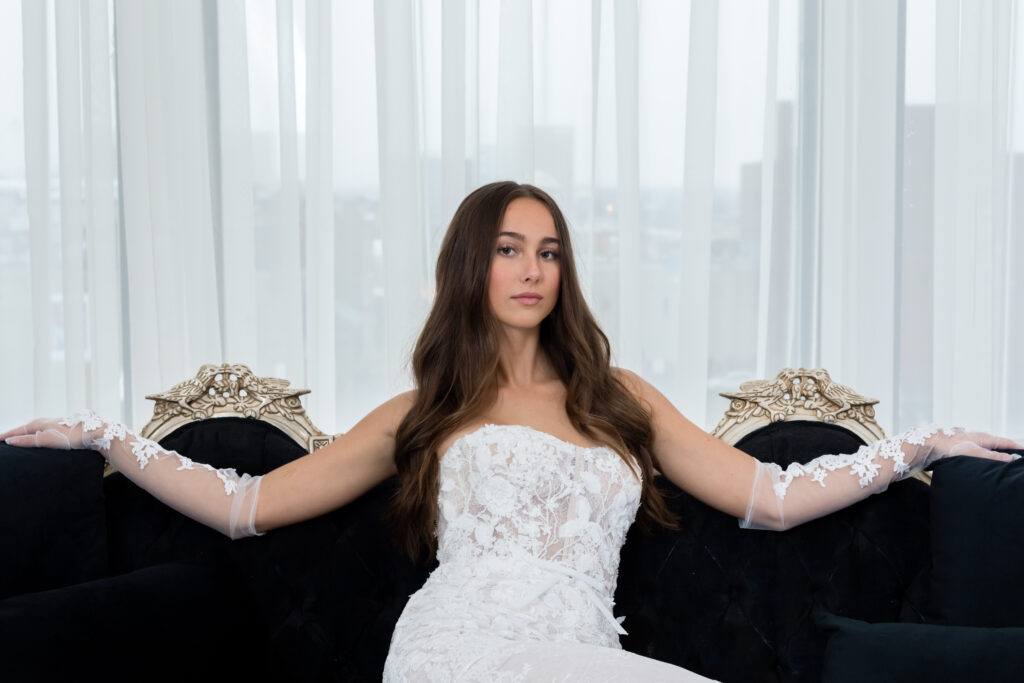 bride lounging on couch wearing wedding dress and white lace gloves with floral detailing