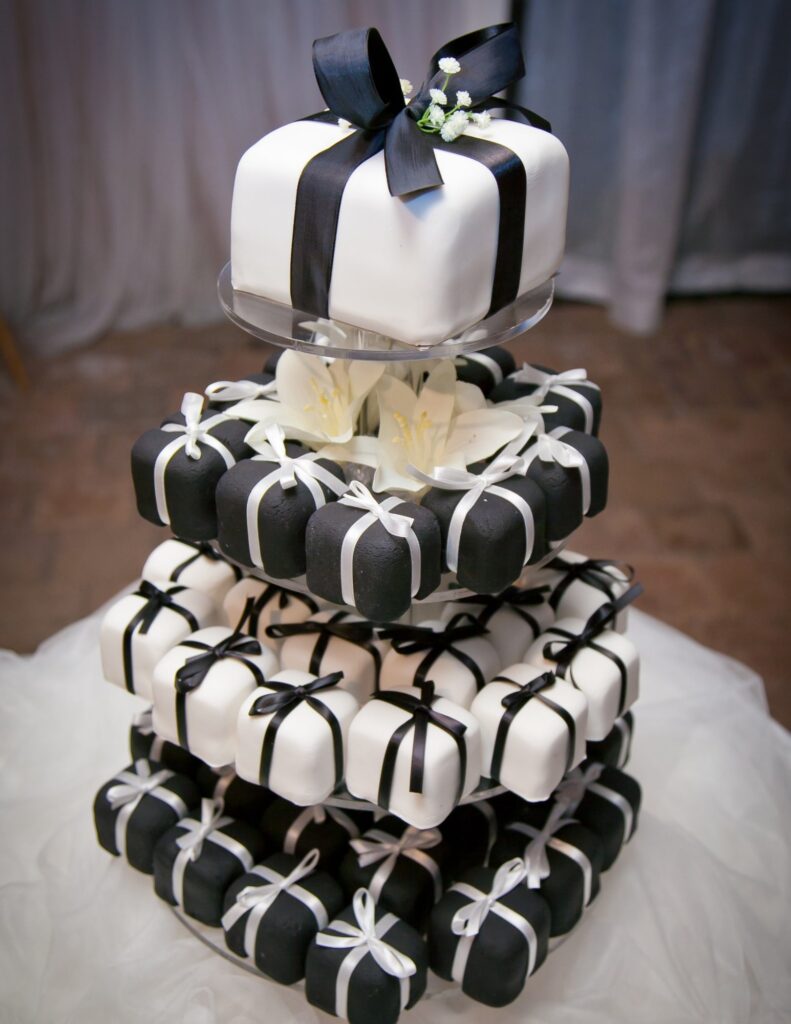 four tiers of monochromatic mini wedding cakes shaped like gift boxes
