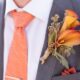 groom wearing a large orange flower as his boutonniere