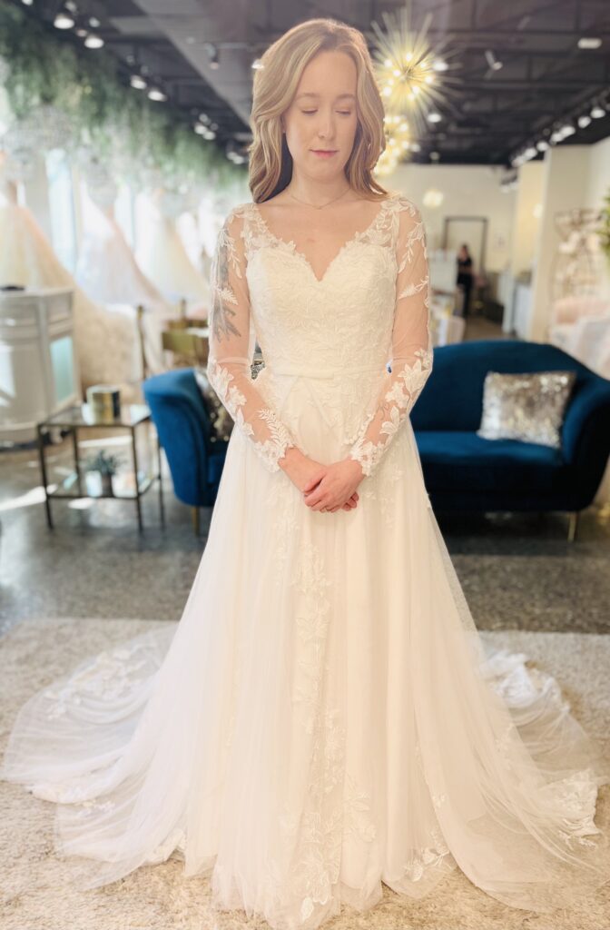Patrice is a flowy Aline with long illusion sleeves. The subtle beading is accentuated by its soft and delicate tulle.