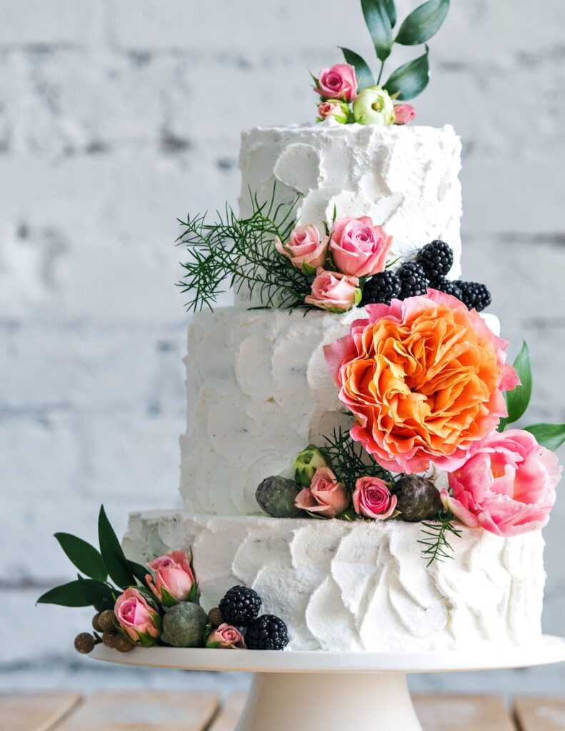 a three-tier wedding cake with bright, vibrant floral elements