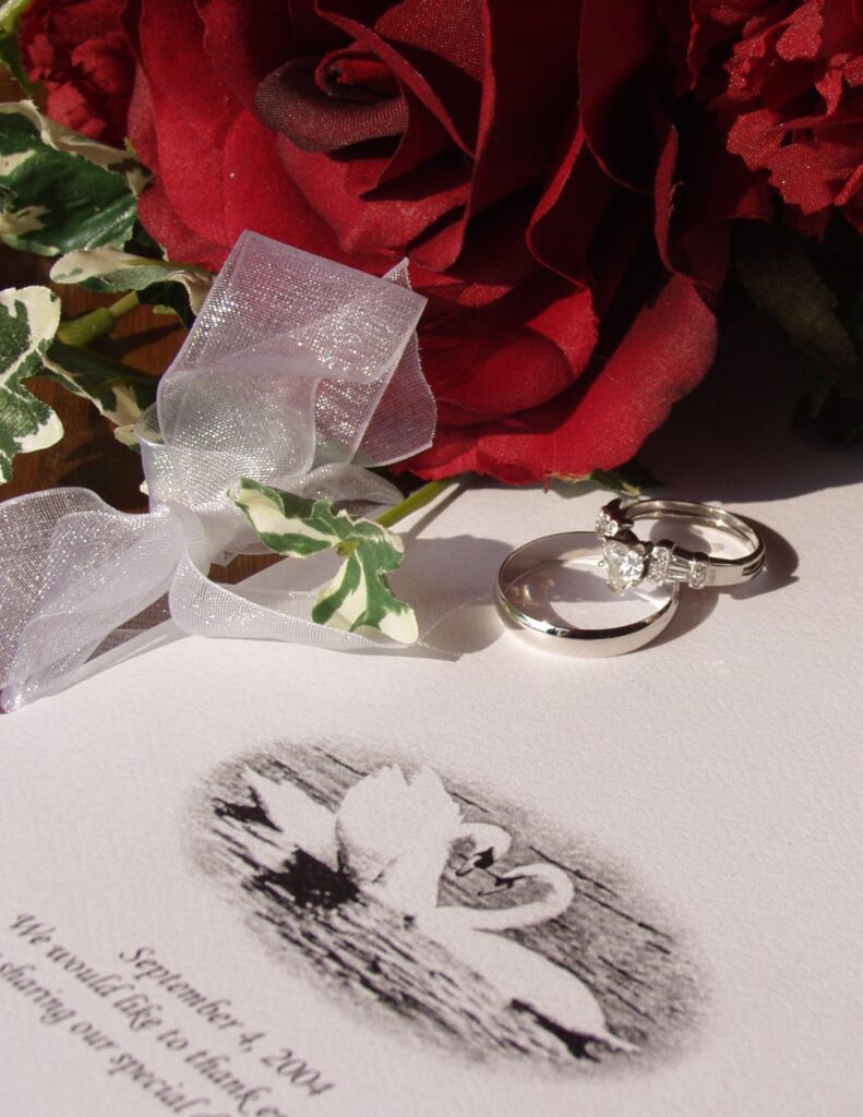 a wedding invitation with two wedding rings resting on it