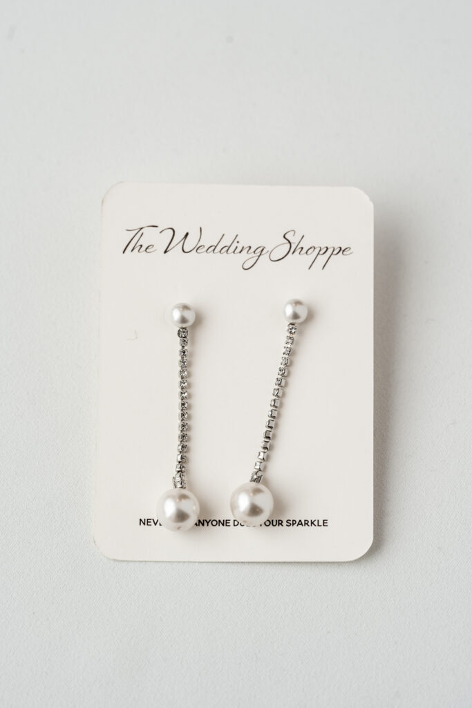 A pair of silver and pearl earrings from The Wedding Shoppe with the words "Never Let Anyone Dull Your Sparkle" underneath