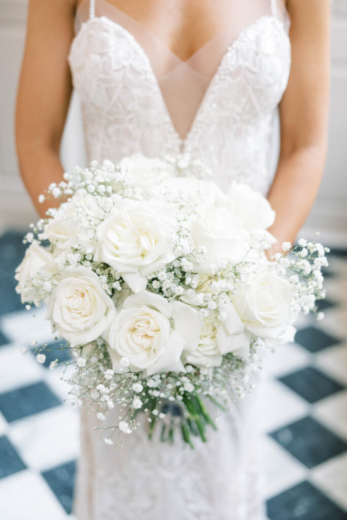a bride holding a bouquet of white roses in a wedding gown