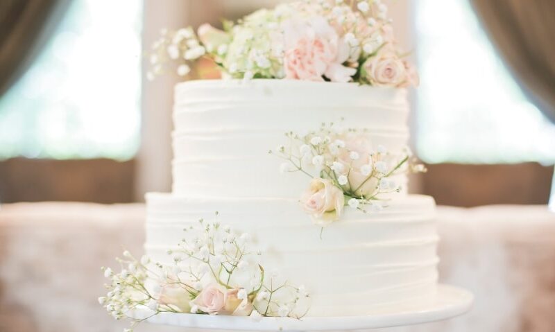 a classic white wedding cake with two tiers and flowers on the cake