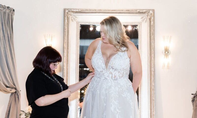 woman in black helping a bride with wedding dress alterations