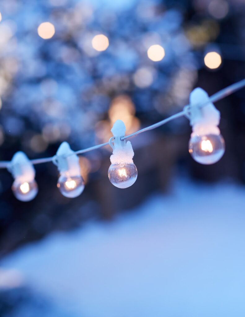 a row of hanging string lights with snow on top of them