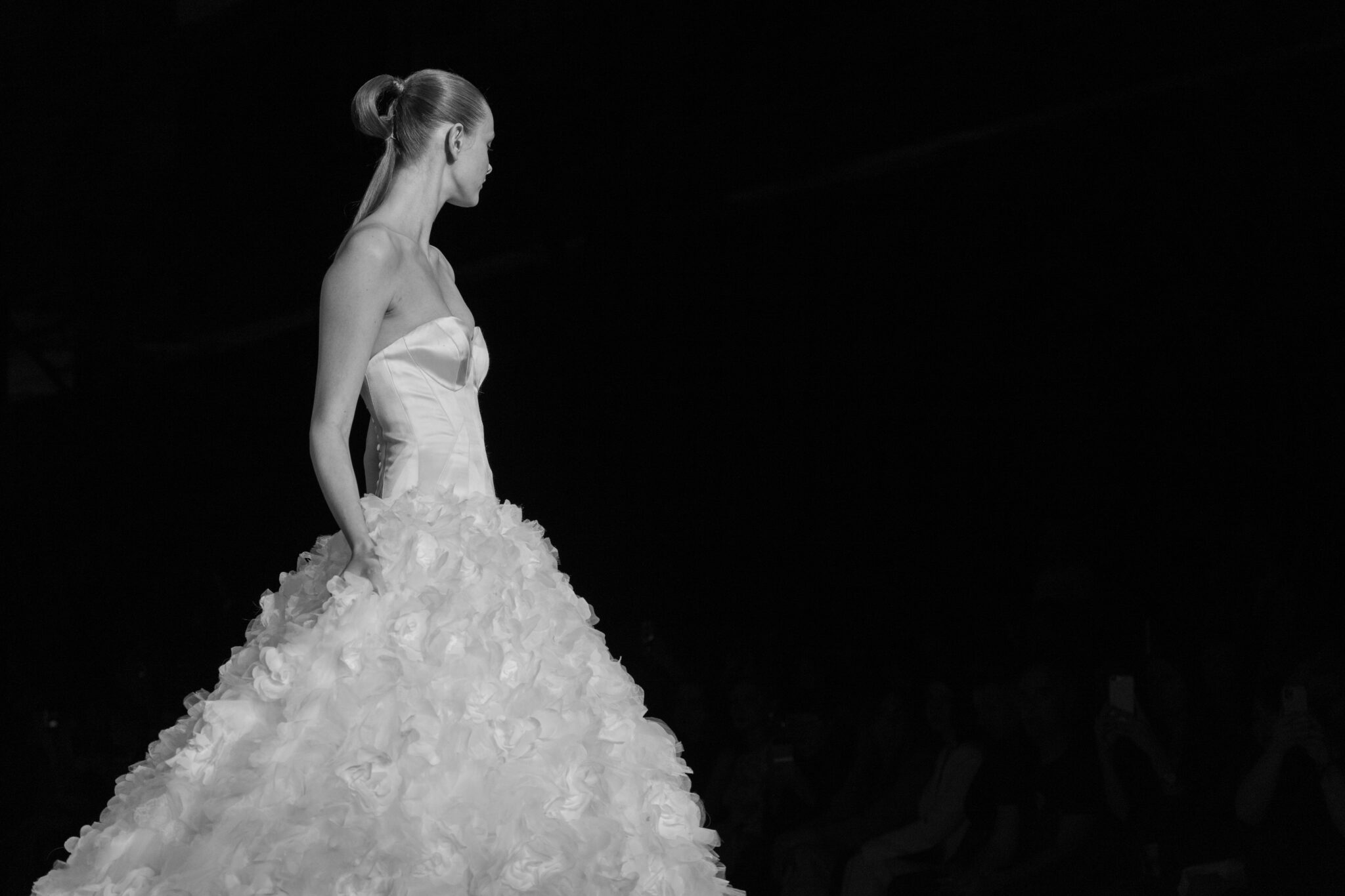black and white image of woman in a Madeline Couture wedding dress standing in pitch black room