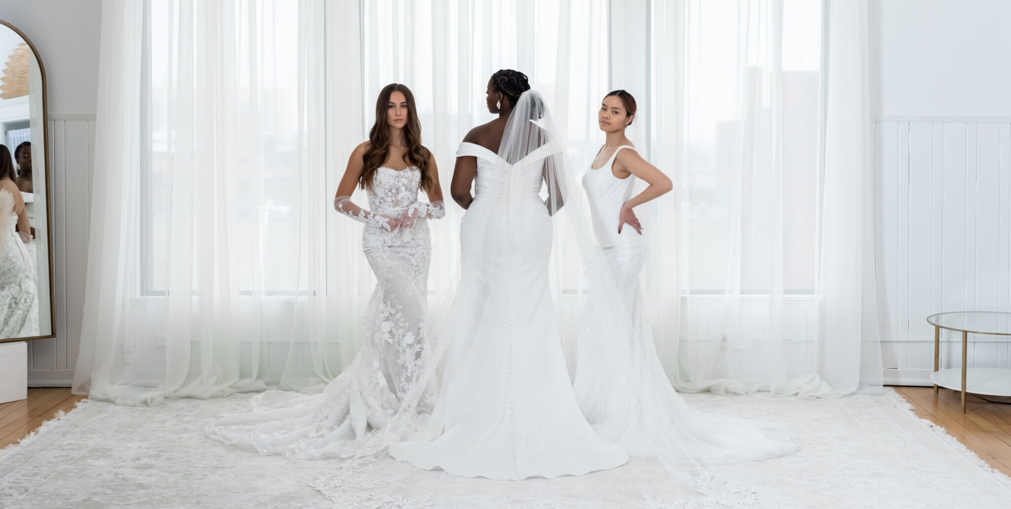 three women in different bridal gowns in white room