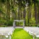 a wedding area with white chairs set up in front of the forest