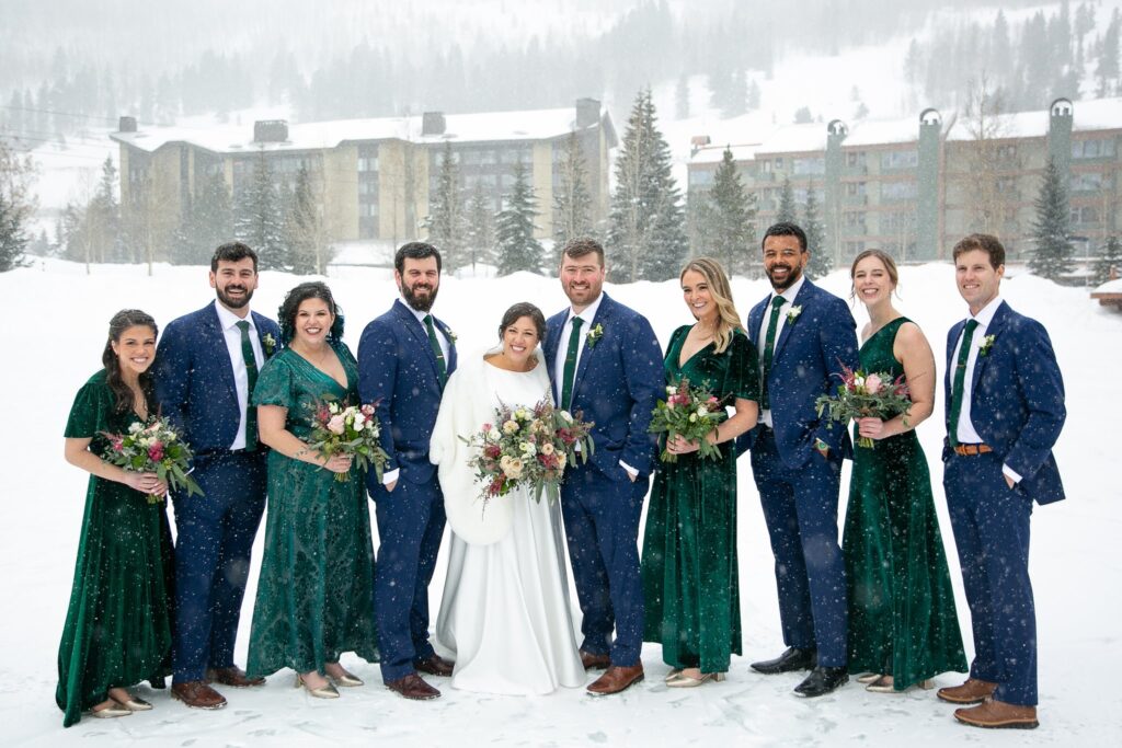 the bride, groom, and their bridal party standing out in the snow