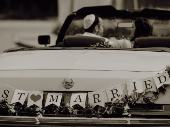 newly married couple driving off in a vintage car with the words "Just Married" on the back