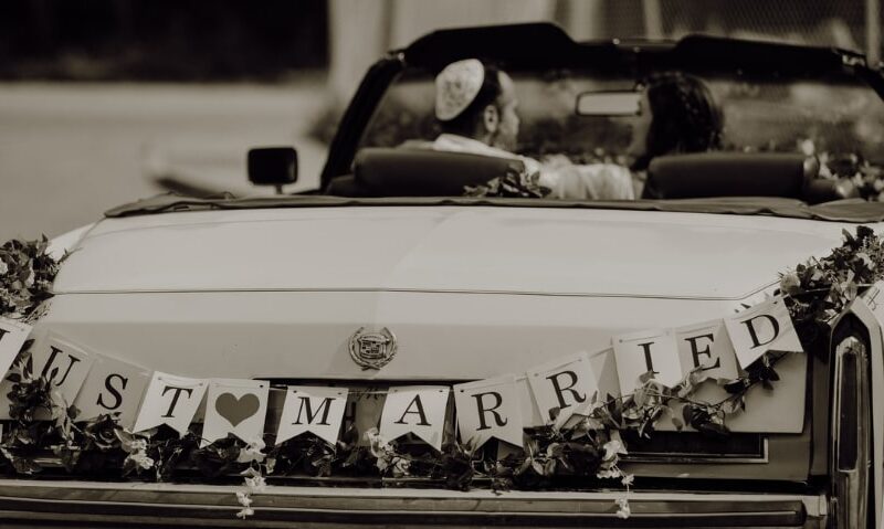 newly married couple driving off in a vintage car with the words "Just Married" on the back