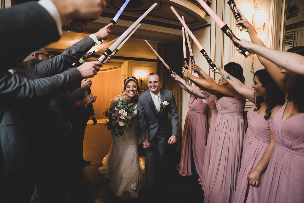 couple exiting their wedding through a lightsaber arch