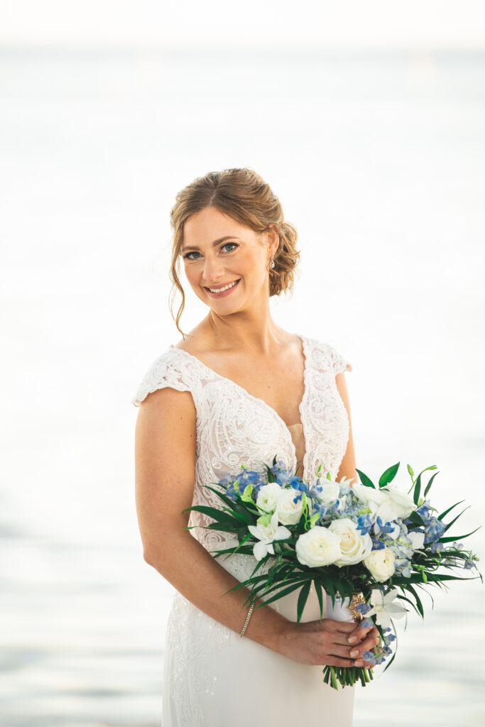 bride smiling holding a bouquet of white and blue flowers