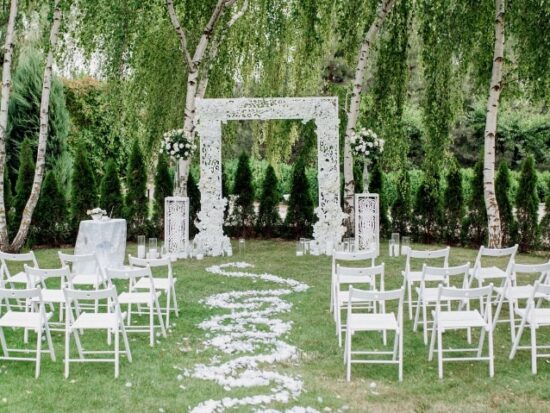 outdoor wedding venue surrounded by greenery and white furniture