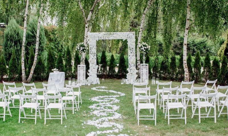 outdoor wedding venue surrounded by greenery and white furniture