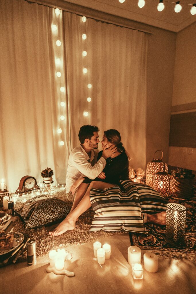 newly married husband and wife sitting on comfortable pillows surrounded by romantic candle lights