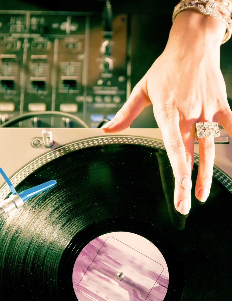 a woman DJ reaching toward her record on a turntable