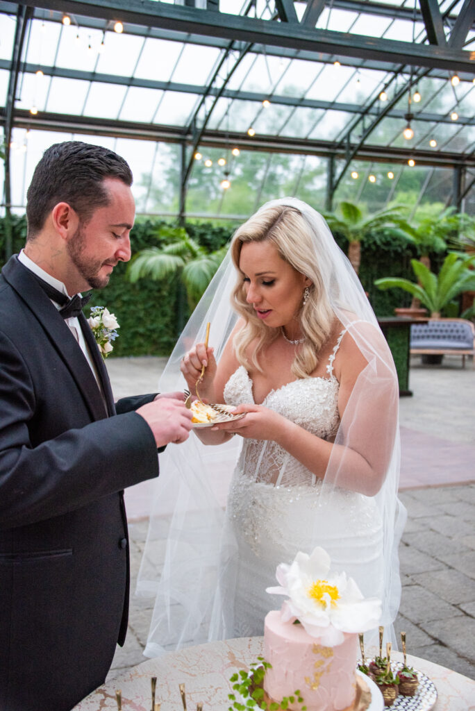 bride and groom sharing a slice of pink wedding cake at the Planterra Conservatory