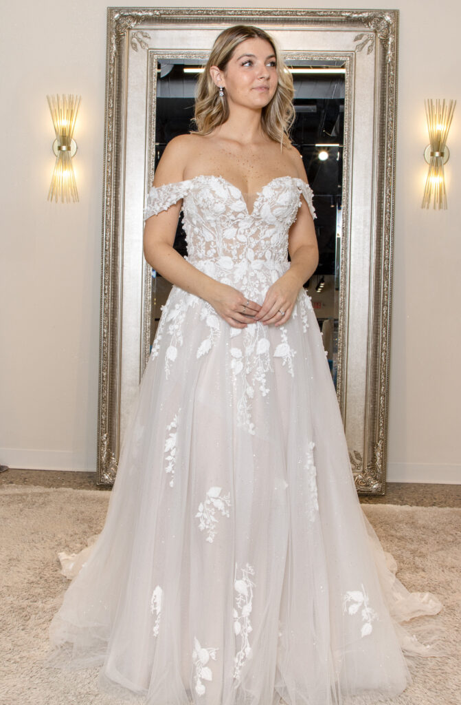 Calise is a sweetheart aline gown with some light sparkle throughout the leafy lace detail. The detachable straps make this a dress with 2 looks in one.