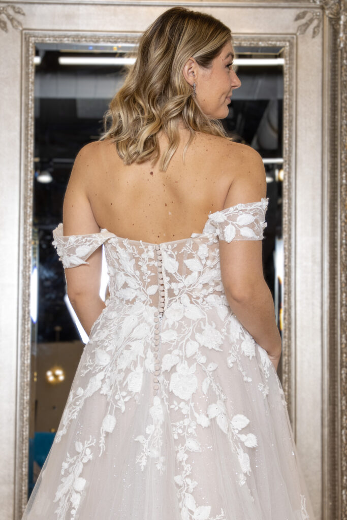 The back of Calise, a sweetheart aline gown with some light sparkle throughout the leafy lace detail. The detachable straps make this a dress with 2 looks in one.