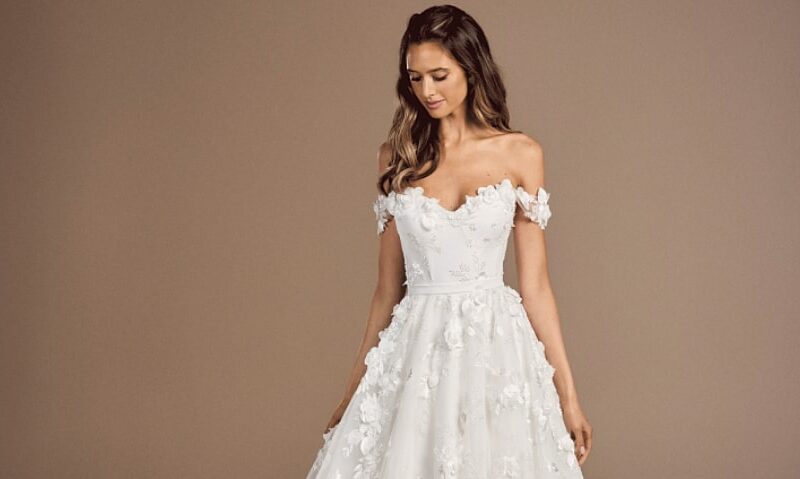 Debussy by Suzanne Neveille is a gown with textured lace applique and off-the-shoulder sleeves