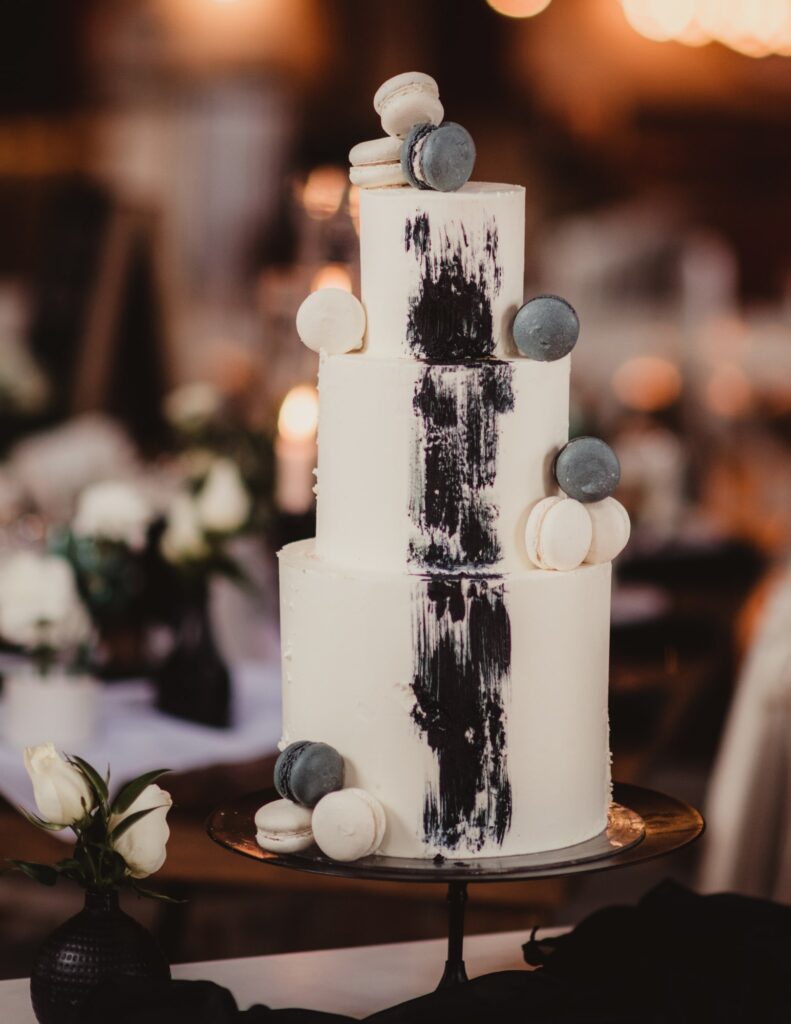 a black and white tiered wedding cake adorned with macarons