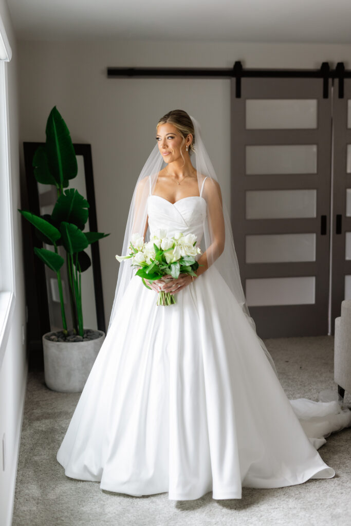 a bride waiting for the wedding holding her green and white bouquet wearing a dress and veil