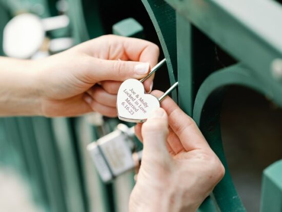 woman locking a heart-shaped lock onto a bridge to signify everlasting love