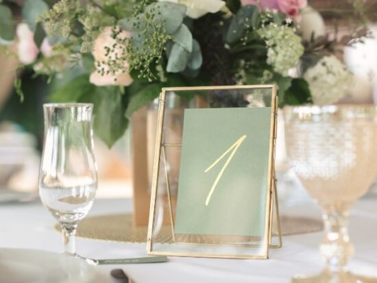 a sage green table setting underneath a bouquet of flowers