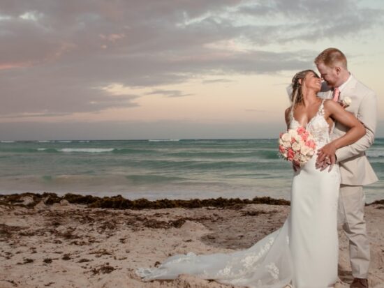 Bride and groom taking wedding photo in front of a sunset on a beach