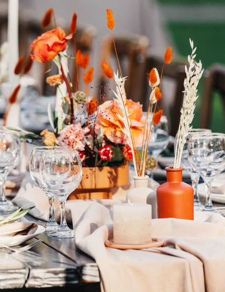 a wedding table decorated with a cloth and orange, red, and white flowers