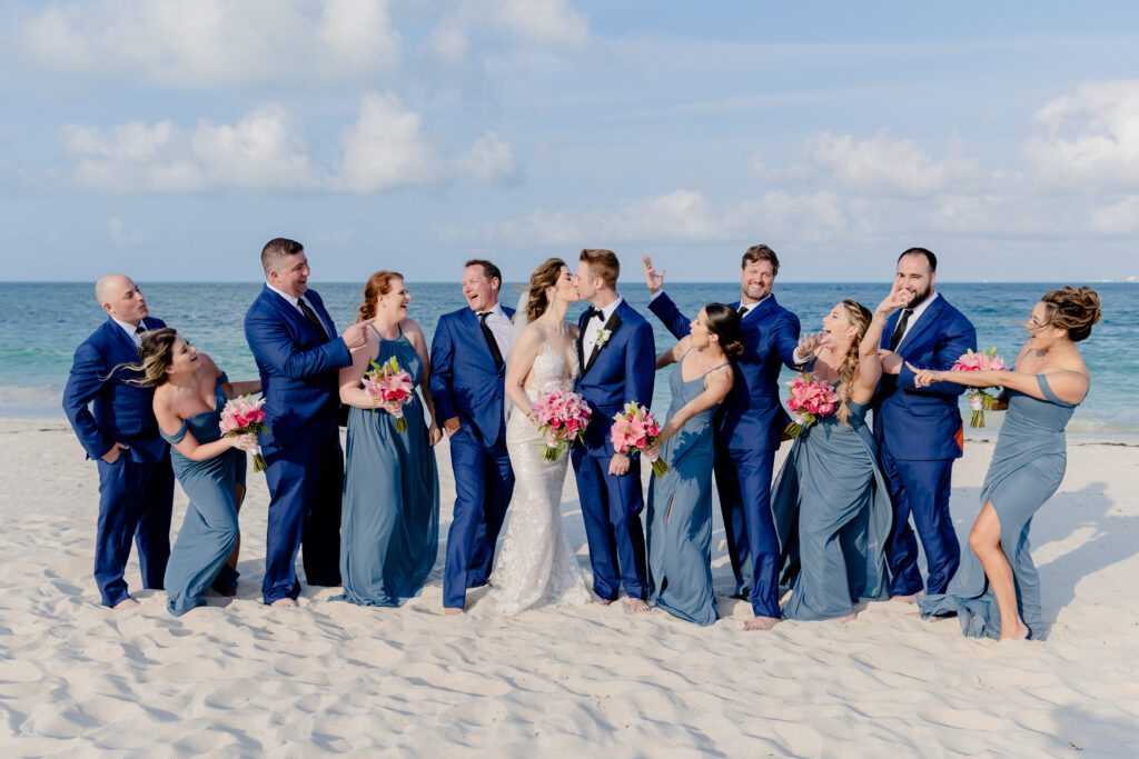a wedding party posing on a beach for a summer wedding