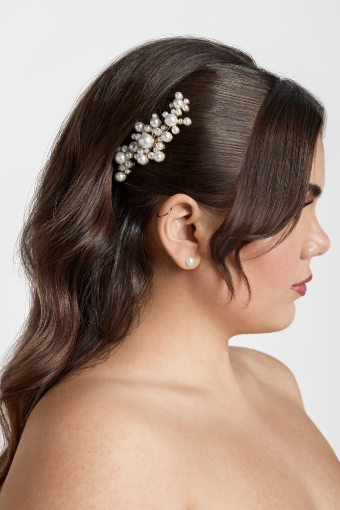 woman wearing a pearl hair comb and a single pearl earring as bridal accessories