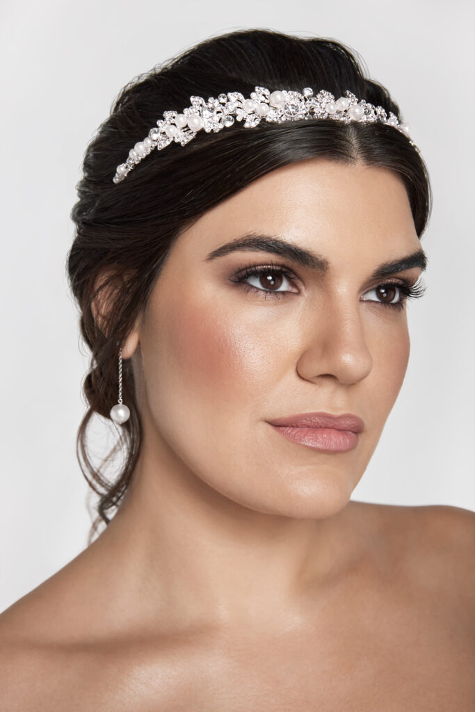 a woman wearing a tiara and a single pearl drop earring for a wedding accessory