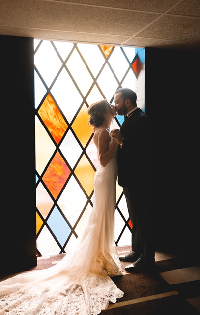 bride and groom kissing in front of a stained glass window