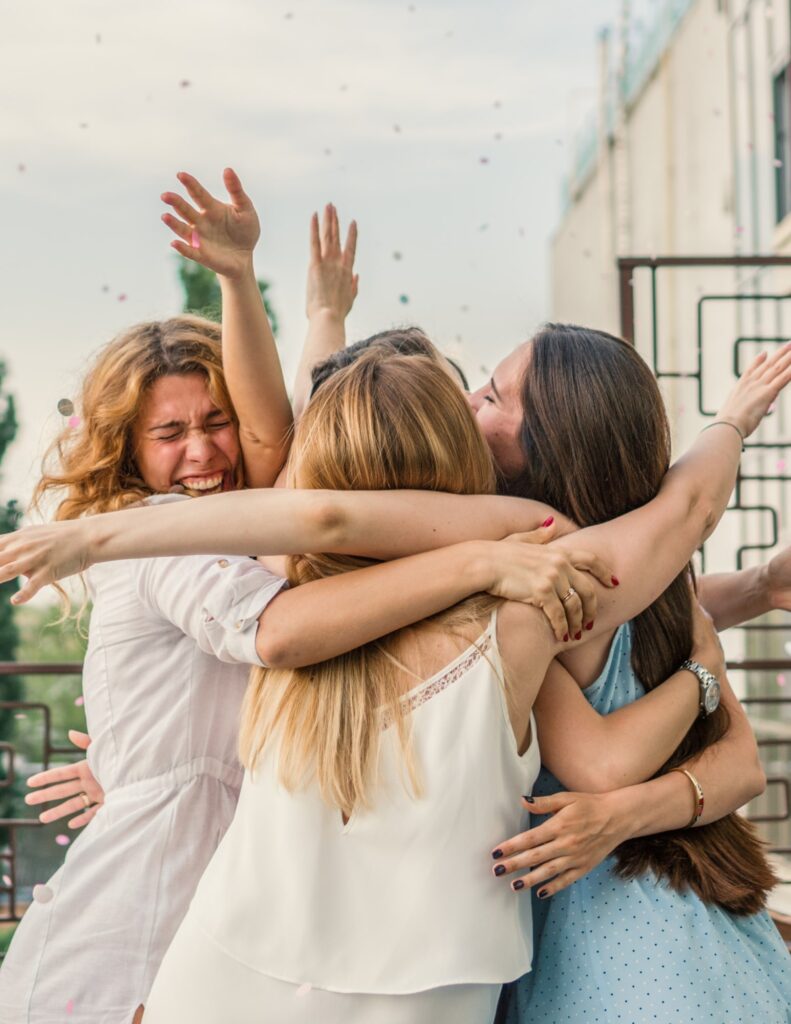 a group of friends hugging as confetti rains down from above at a bachelorette party