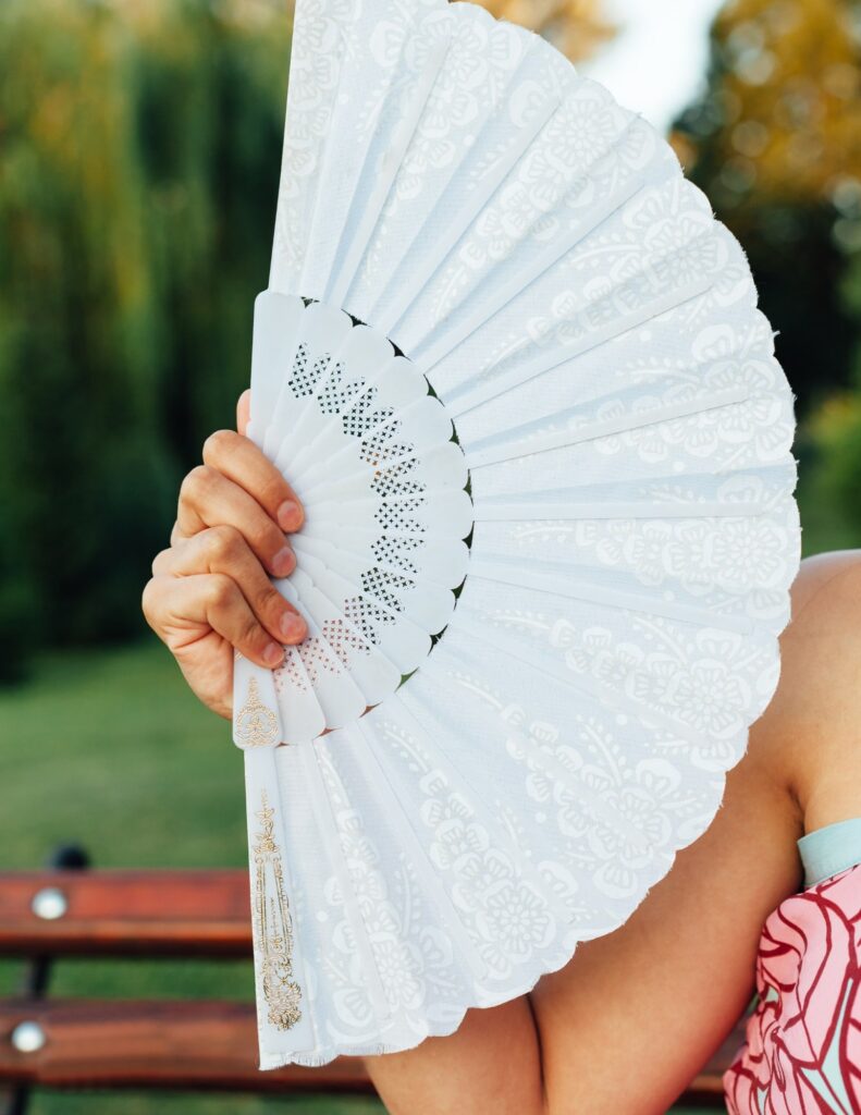 a woman holding a handheld fan for a summer wedding favor