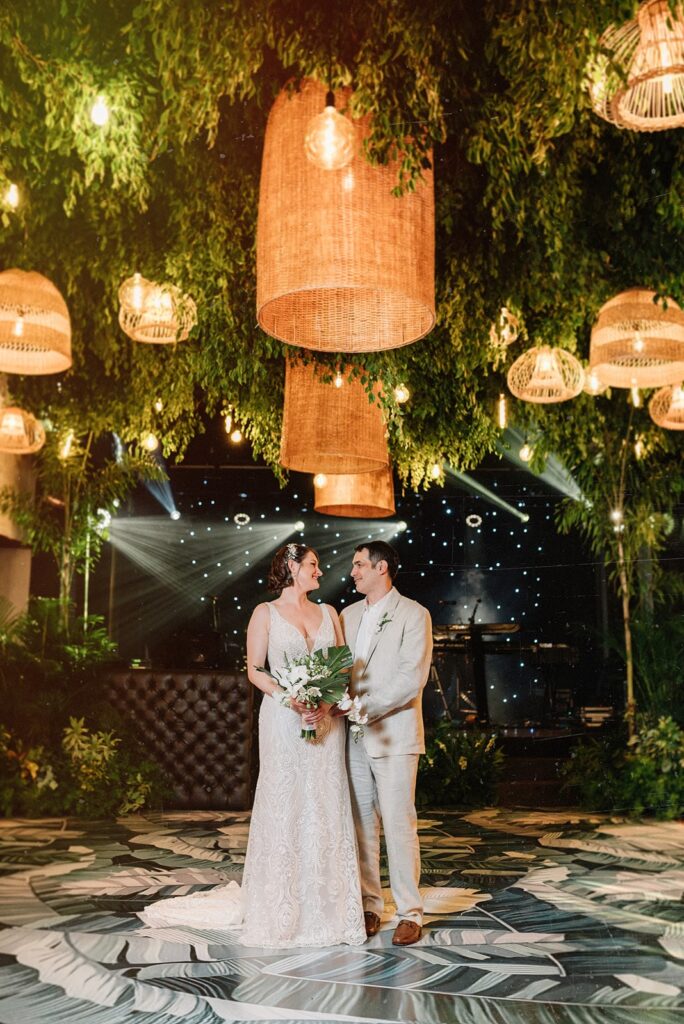husband and wife at their wedding under lanterns and hanging plants