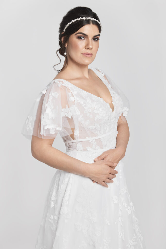 Mila is a lightweight, lace a-line wedding gown with a soft flutter sleeve.