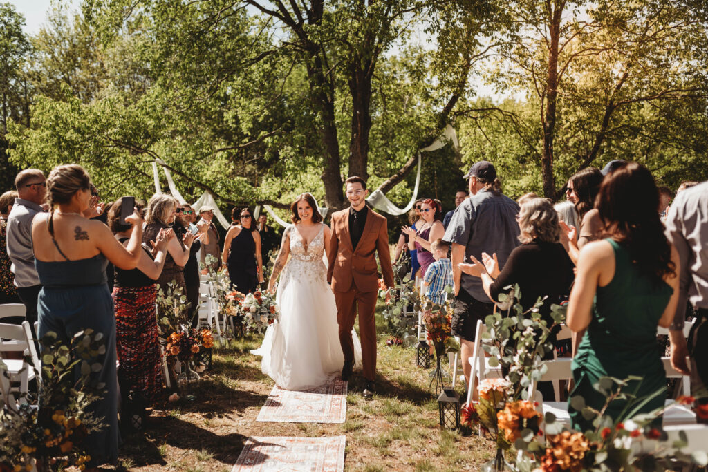 an outdoor forest wedding with a series of rustic carpets as the wedding aisle