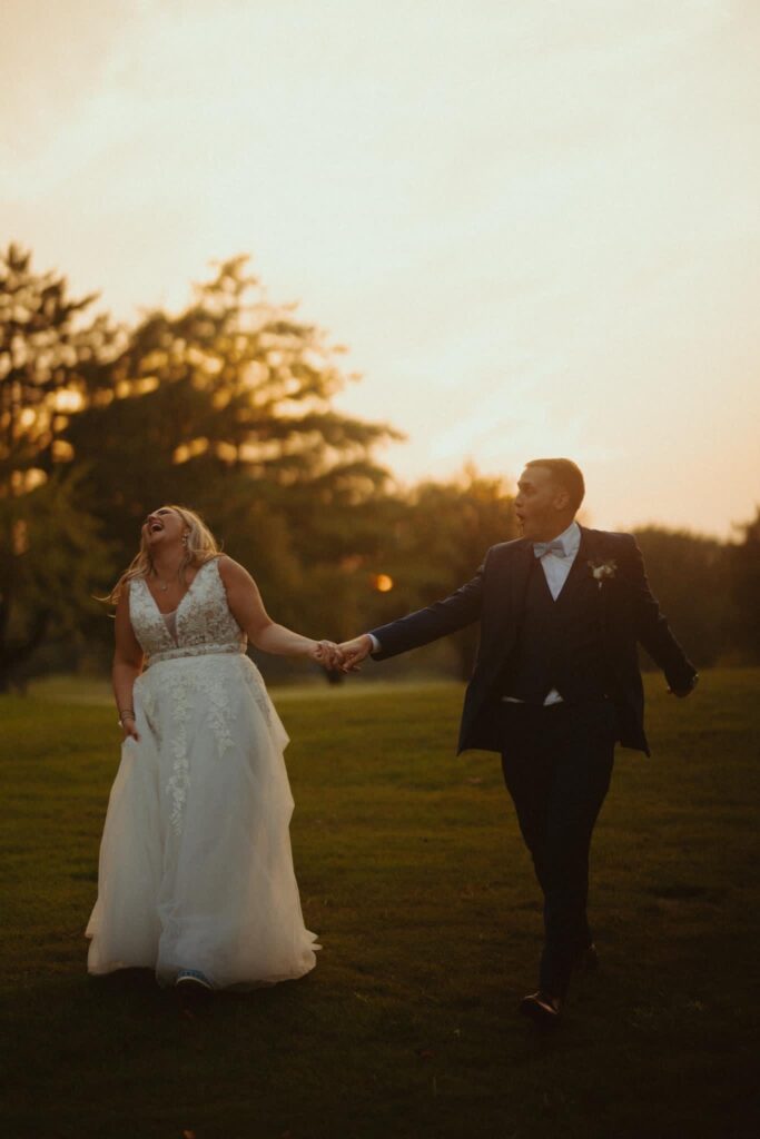 husband and wife in a field after their summer wedding at sunset
