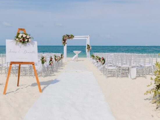 a beach wedding setting with floral bouquets as aisle decorations