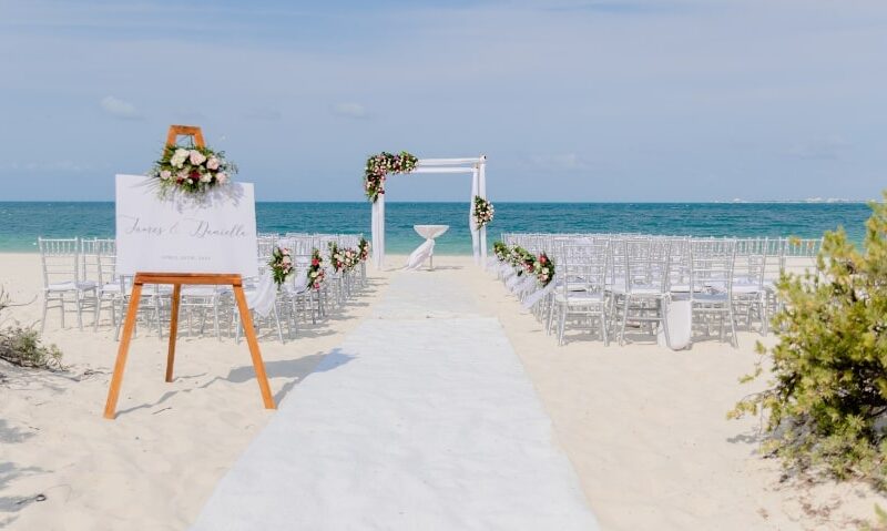 a beach wedding setting with floral bouquets as aisle decorations