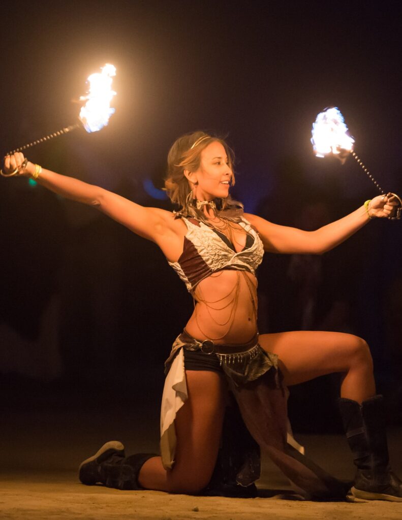 a female fire dancer holding two flaming torches for a fantasy wedding