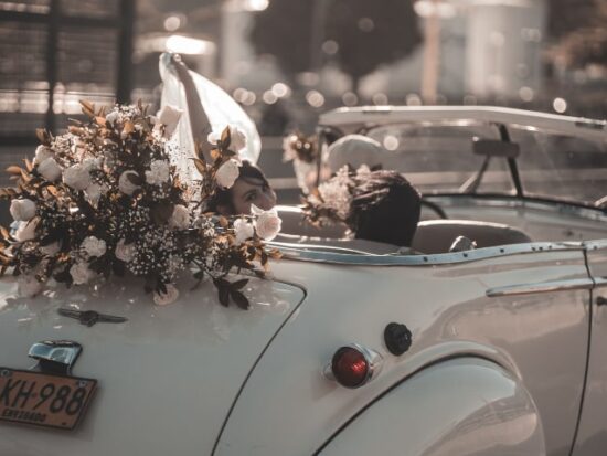 bride and groom driving away from the wedding in a vintage car adorned with flowers, perfect for an old hollywood wedding