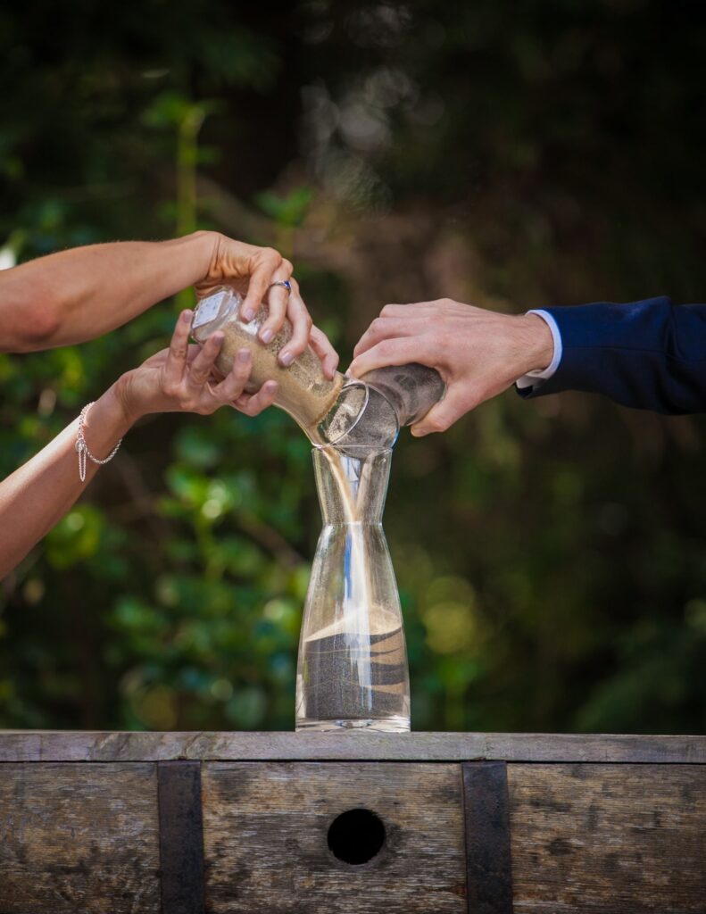 a wedding couple pouring different colored sand into a vase as a wedding tradition