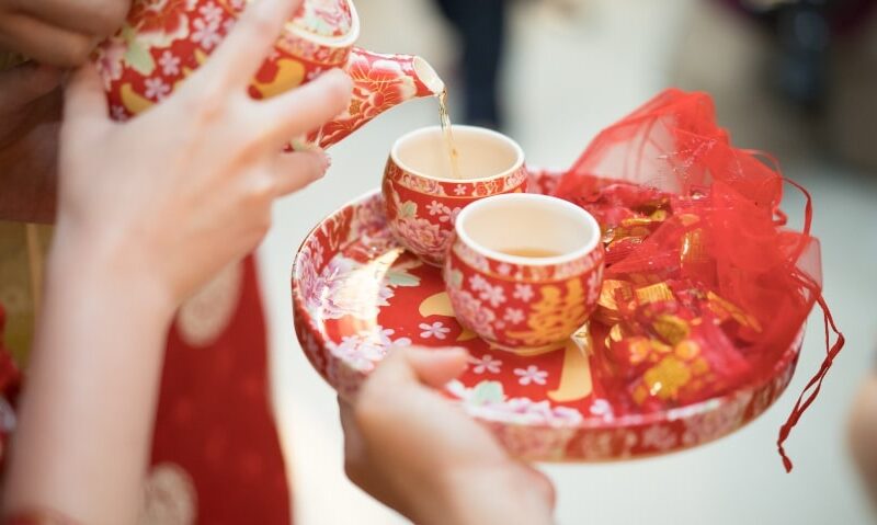woman pouring tea into an intricately decorated cup as a wedding tradition